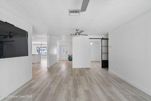 921 S Orlando Ave, Cocoa Beach, FL 32931 - unfurnished living room with ceiling fan, a textured ceiling, light wood-style floors, a barn door, and baseboards