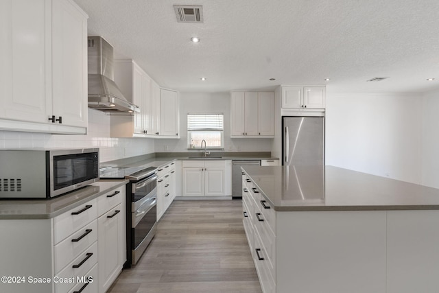 921 S Orlando Ave, Cocoa Beach, FL 32931 - kitchen featuring appliances with stainless steel finishes, wall chimney range hood, a sink, a textured ceiling, and a kitchen island