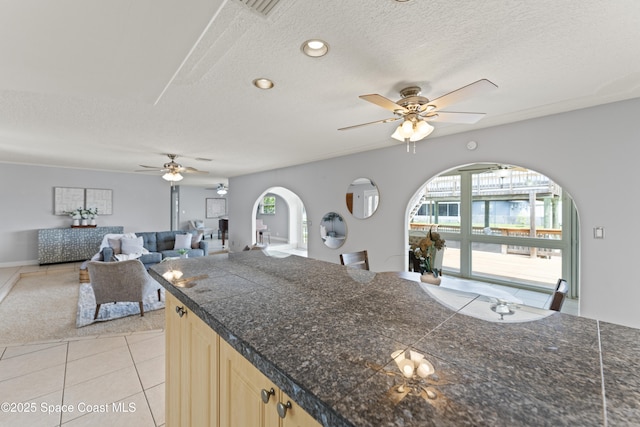 1700 Neptune Dr, Merritt Island, FL 32952 - kitchen with tile counters, ceiling fan, light brown cabinets, arched walkways, and a textured ceiling