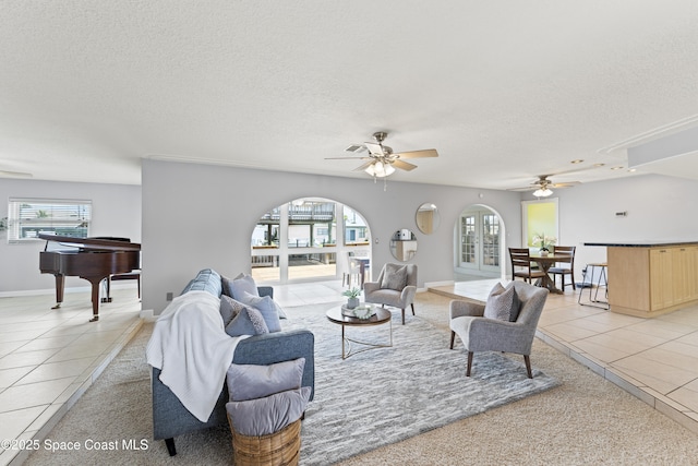 1700 Neptune Dr, Merritt Island, FL 32952 - living area featuring ceiling fan, a textured ceiling, light tile patterned flooring, arched walkways, and baseboards