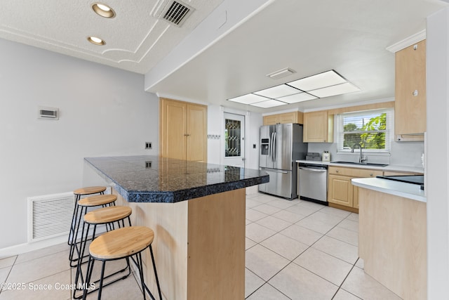 1700 Neptune Dr, Merritt Island, FL 32952 - kitchen with appliances with stainless steel finishes, light brown cabinetry, tile counters, a sink, and a breakfast bar area