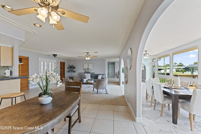 1700 Neptune Dr, Merritt Island, FL 32952 - dining space featuring arched walkways, a ceiling fan, light tile patterned floors, baseboards, and light carpet