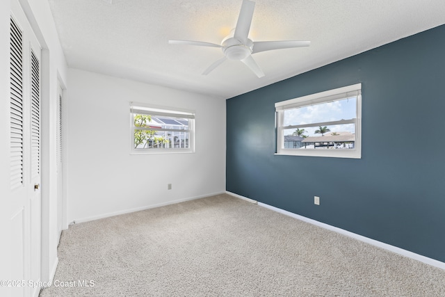 1700 Neptune Dr, Merritt Island, FL 32952 - unfurnished bedroom featuring carpet flooring, a textured ceiling, baseboards, a closet, and a ceiling fan
