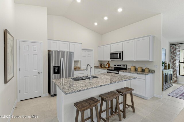 3356 Framingham Ave, Palm Bay, FL 32908 - kitchen featuring a sink, appliances with stainless steel finishes, white cabinets, light stone countertops, and a center island with sink