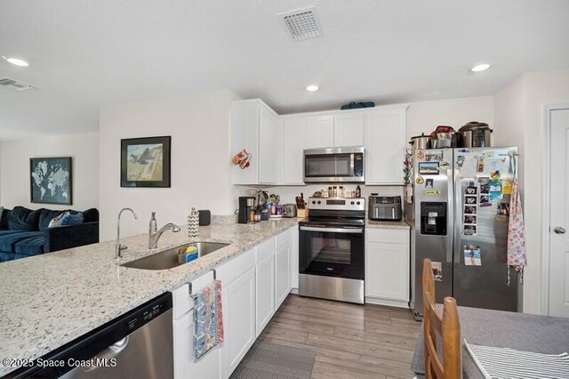 966 Stage St SE, Palm Bay, FL 32909 - kitchen with appliances with stainless steel finishes, a sink, light wood-style floors, light stone countertops, and white cabinetry