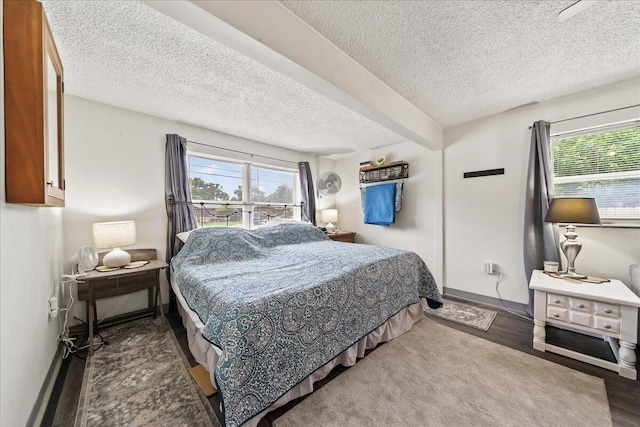 bedroom with multiple windows, a textured ceiling, baseboards, and wood finished floors