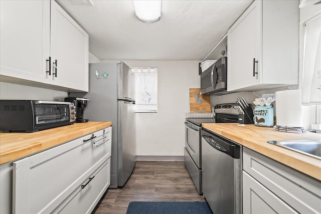 kitchen featuring butcher block countertops, stainless steel appliances, white cabinetry, and dark wood-style flooring