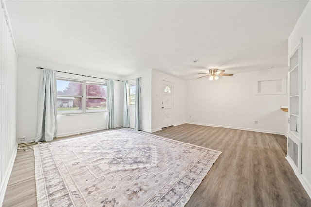 unfurnished living room with light wood-style floors, ceiling fan, and baseboards