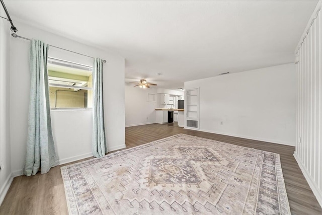 unfurnished living room featuring wood finished floors, ceiling fan, and baseboards