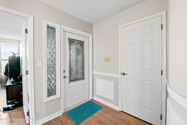 foyer entrance with a textured ceiling, wood finished floors, and baseboards