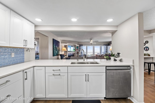 kitchen with a sink, stainless steel dishwasher, a peninsula, white cabinets, and recessed lighting