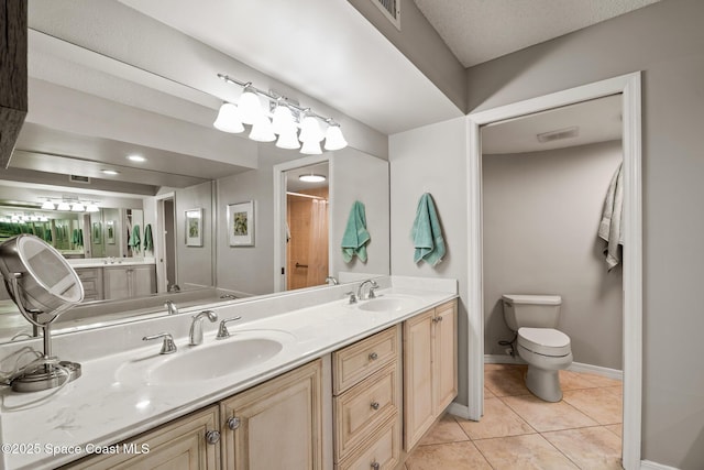 bathroom featuring tile patterned floors, toilet, double vanity, and baseboards