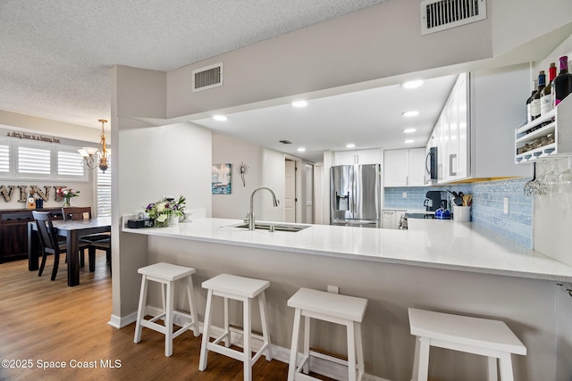 kitchen with stainless steel appliances, a peninsula, a sink, light wood-type flooring, and recessed lighting