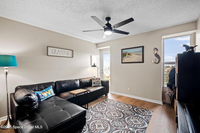 living area featuring wood finished floors, a ceiling fan, a textured ceiling, and baseboards