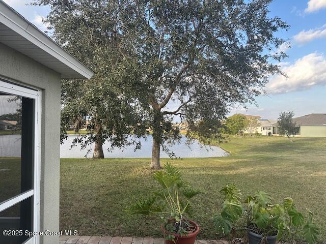 view of green lawn featuring a water view