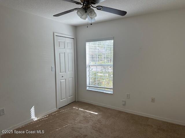 spare room featuring carpet flooring, ceiling fan, baseboards, and a textured ceiling