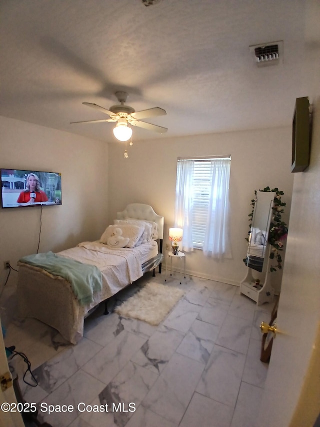 bedroom with marble look tiles and a ceiling fan