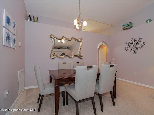 dining area with arched walkways, light carpet, and baseboards