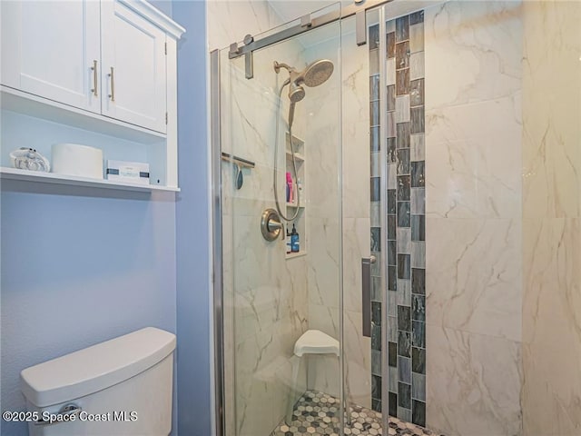 bathroom with a shower stall and toilet