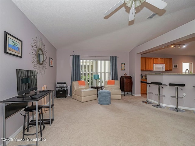 living room with lofted ceiling, light colored carpet, a ceiling fan, and baseboards