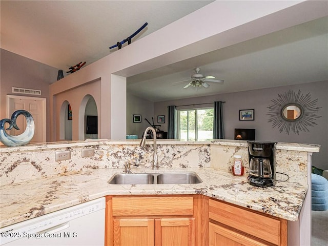 kitchen with white dishwasher, a sink, light stone countertops, open floor plan, and ceiling fan