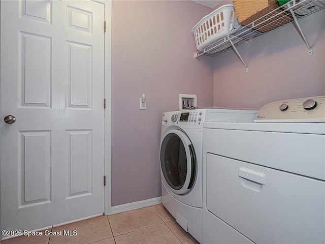 washroom featuring washer and clothes dryer, light tile patterned floors, and baseboards