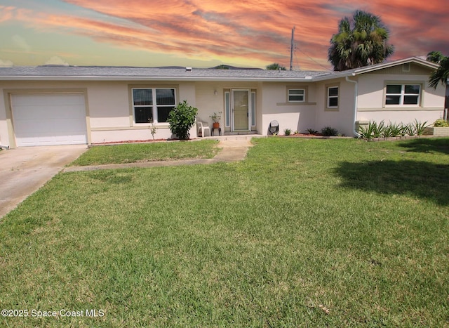 ranch-style house featuring stucco siding, a garage, concrete driveway, and a front lawn