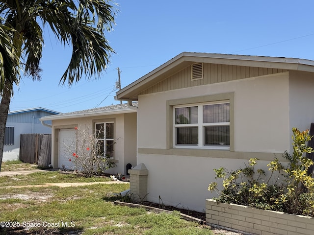 view of side of home with stucco siding and a garage