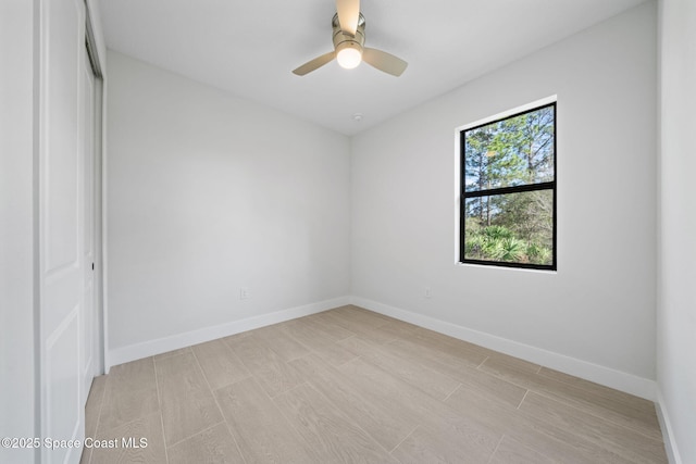 spare room featuring a ceiling fan, baseboards, and light wood finished floors