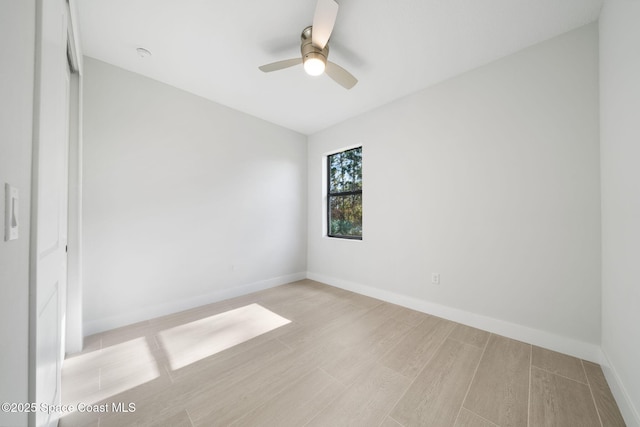 empty room with a ceiling fan, light wood-style flooring, and baseboards