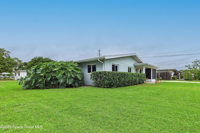 2341 Pawnee Dr, Melbourne, FL 32935 - view of side of property with stucco siding, a yard, and driveway