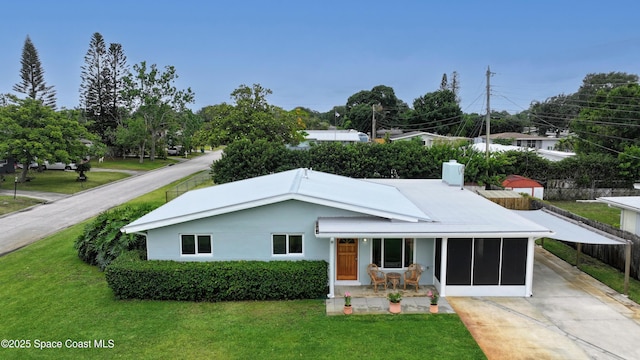 2341 Pawnee Dr, Melbourne, FL 32935 - view of front facade with concrete driveway, a sunroom, an attached carport, and a chimney