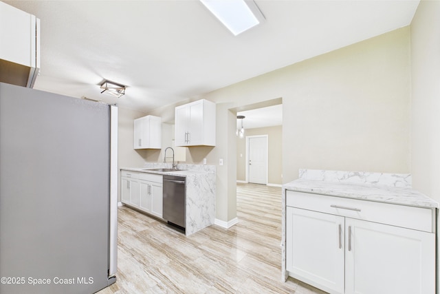 2341 Pawnee Dr, Melbourne, FL 32935 - kitchen featuring stainless steel appliances, a sink, white cabinetry, light wood-style flooring, and baseboards