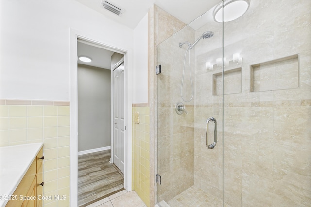 2341 Pawnee Dr, Melbourne, FL 32935 - bathroom with tile walls, a shower stall, vanity, a wainscoted wall, and tile patterned flooring