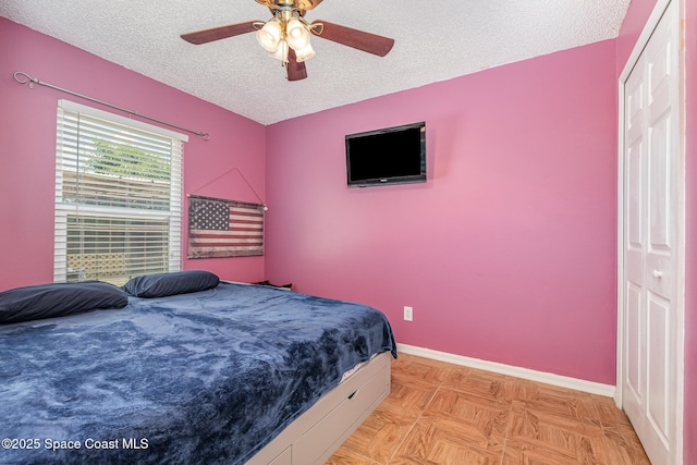 bedroom featuring a textured ceiling, baseboards, and a ceiling fan
