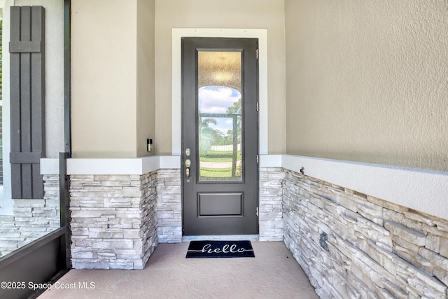 entrance to property featuring stone siding and stucco siding