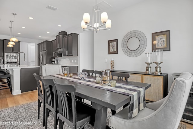 dining room featuring light wood-style flooring, recessed lighting, and a chandelier