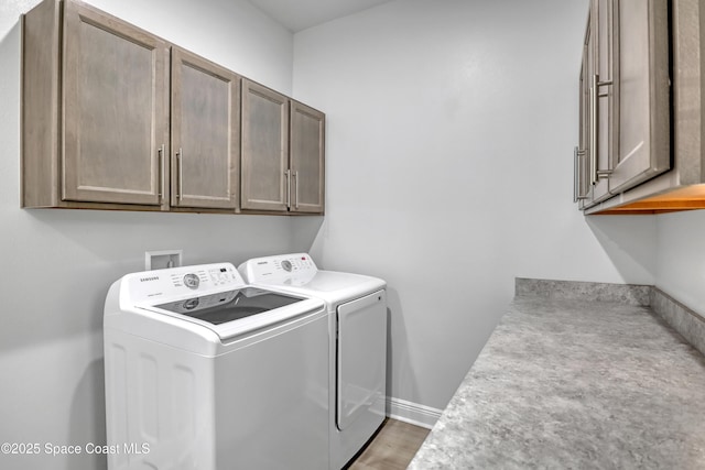 clothes washing area with cabinet space, washer and clothes dryer, and baseboards