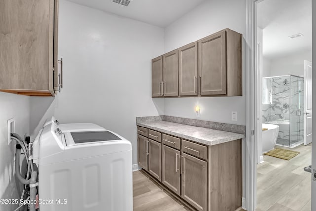 clothes washing area with cabinet space, light wood-style flooring, and independent washer and dryer