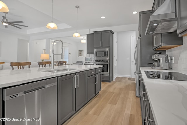 kitchen featuring stainless steel appliances, a sink, wall chimney exhaust hood, recessed lighting, and tasteful backsplash