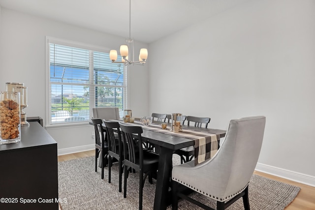 dining space with light wood-type flooring, baseboards, and a chandelier