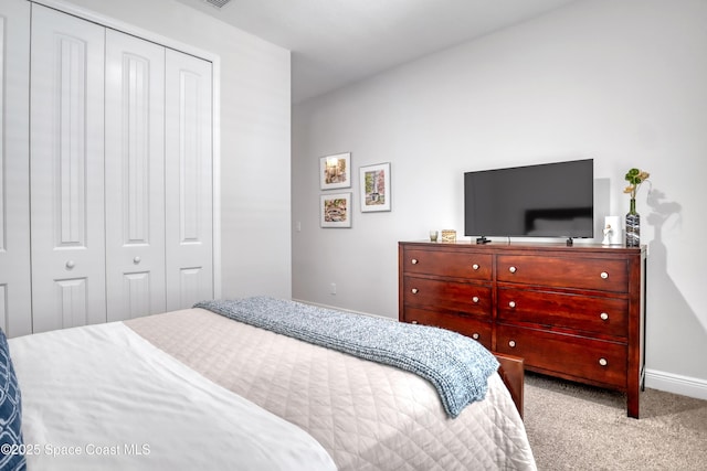 carpeted bedroom with a closet and baseboards