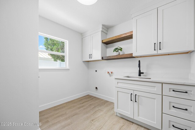 laundry room featuring cabinet space, washer hookup, electric dryer hookup, light wood-style flooring, and baseboards