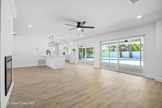 unfurnished living room featuring ceiling fan, baseboards, light wood-type flooring, recessed lighting, and a textured ceiling
