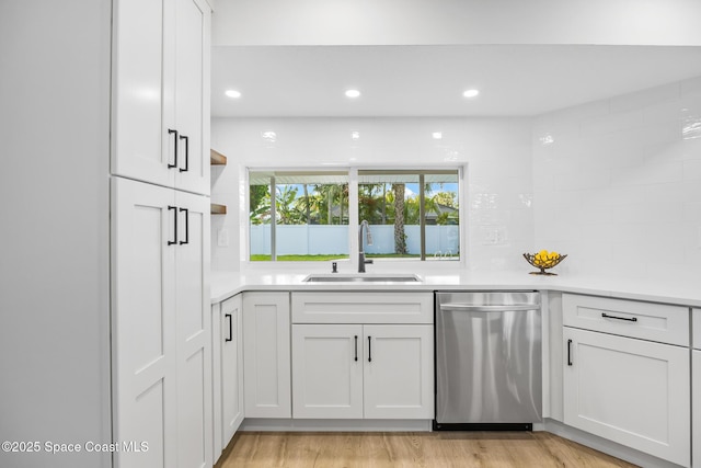 kitchen featuring dishwasher, a sink, light countertops, recessed lighting, and white cabinetry