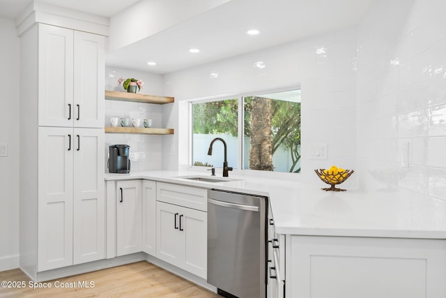 kitchen featuring stainless steel dishwasher, a sink, open shelves, light countertops, and white cabinetry