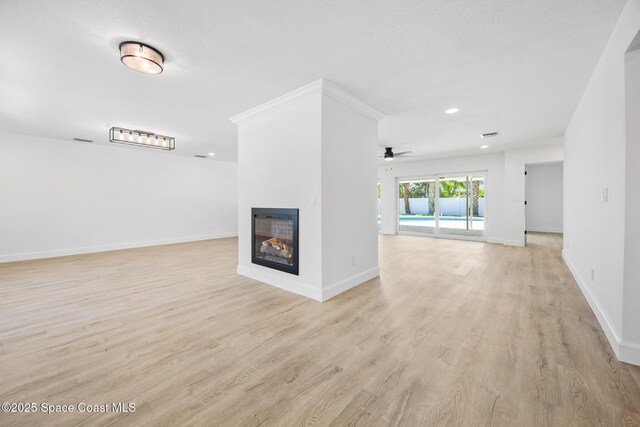 unfurnished living room with a multi sided fireplace, baseboards, light wood-style floors, a ceiling fan, and recessed lighting