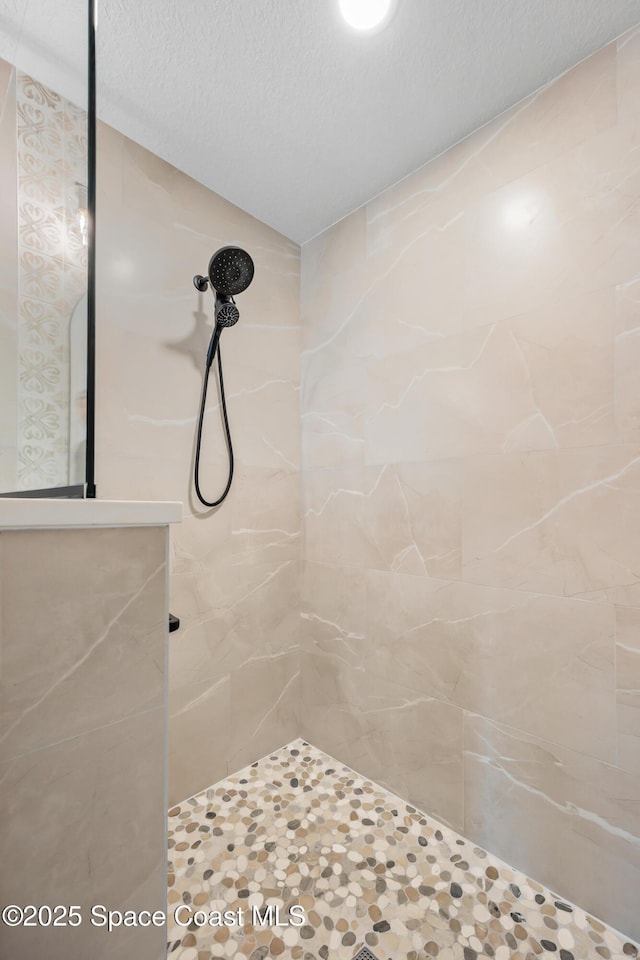 bathroom featuring tiled shower and a textured ceiling