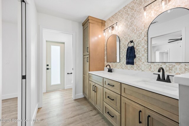 bathroom with wood finished floors, double vanity, tasteful backsplash, and baseboards