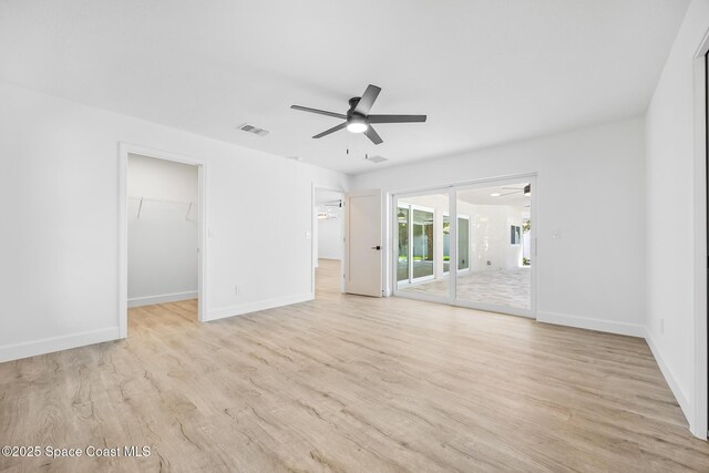 unfurnished bedroom with access to outside, light wood-type flooring, a spacious closet, and baseboards